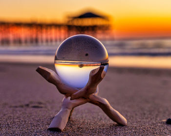 Close-up of sunglasses on beach against sunset sky