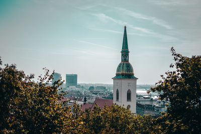 Tower amidst trees and buildings against sky