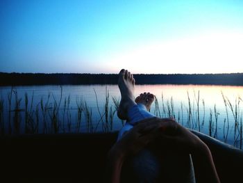 Woman relaxing on lake against sky