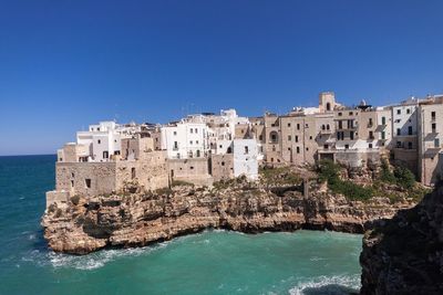 View of built structures against calm blue sea