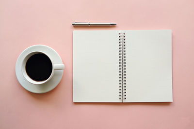 Directly above shot of coffee by diary and pen on table