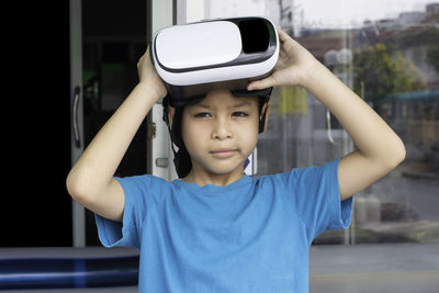 Portrait of boy holding camera while standing outdoors