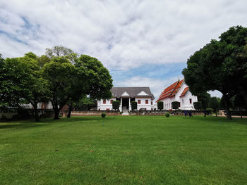 Trees and houses on field against sky