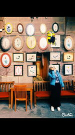 Full length portrait of woman standing at illuminated shop