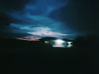 Illuminated road against sky at night