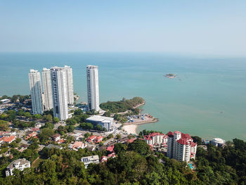 High angle view of buildings by sea against clear sky