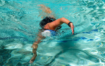 Looking down at a close up of one female swimming laps in an outdoor pool.