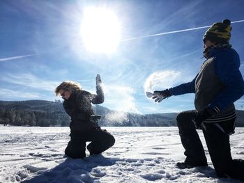 Woman with arms outstretched on snow during sunny day
