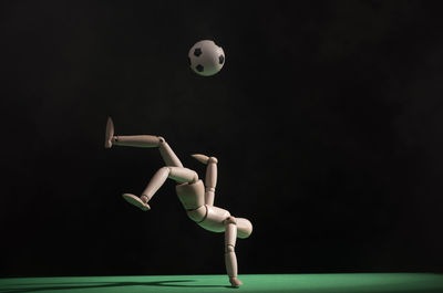 Close-up of figurine playing soccer against black background