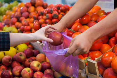 Woman buying fresh vegetables at street market.