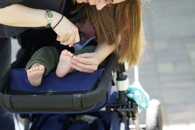 Woman cutting son fingernails on baby stroller