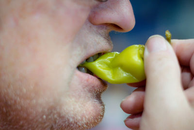 Close-up of man eating chili pepper