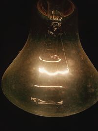 Close-up of light bulb hanging against black background