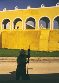 Rear view of woman standing against yellow sky