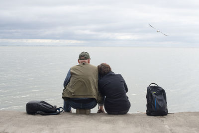 Rear view of man standing by sea against sky