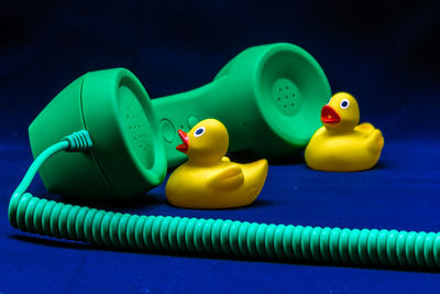 Close-up of yellow rubber ducks and telephone receiver on blue textile