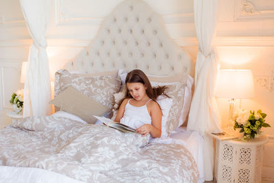 Young woman sitting on bed at home