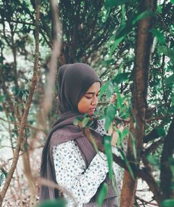 Woman standing by tree in forest