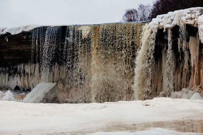 Frozen waterfall against sky during winter