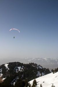 People in mid-air during winter against sky