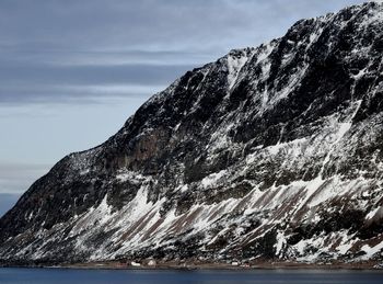 Scenic view of sea by mountain against sky