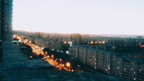 Illuminated city by river against clear sky at night