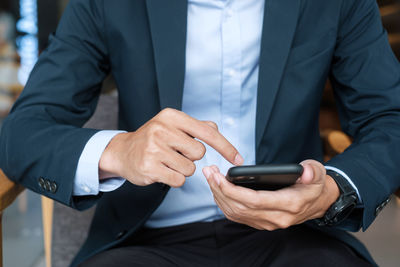 Midsection of man using mobile phone