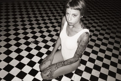 High angle portrait of woman sitting on tiled floor