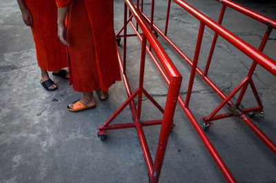 Low section of men standing by red metallic barricades on street