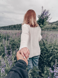 Cropped hand of man holding woman standing on field