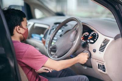 Side view of boy sitting in car