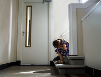 Rear view of sitting on stairs against door 