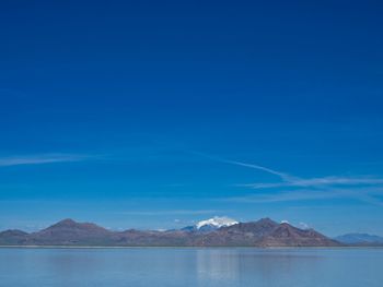 Scenic view of lake and mountains against blue sky