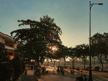 Street amidst trees against sky during sunset