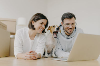 Man using laptop by dog and woman at home