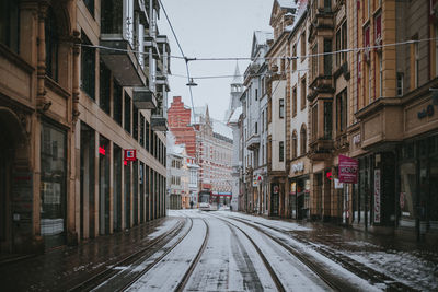 Empty road amidst buildings in city