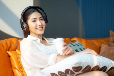 Portrait of young woman sitting on sofa at home