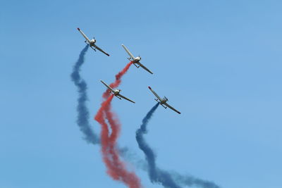 Low angle view of airshow against clear blue sky