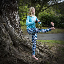 Young woman exercising by tree at park
