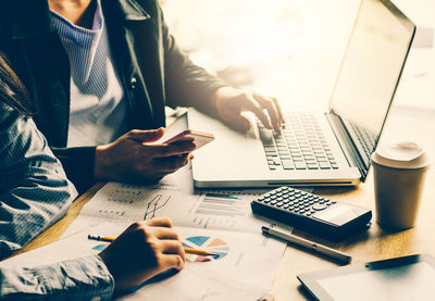 Midsection of colleagues working at table in office