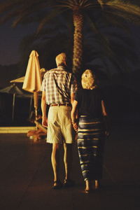 Rear view of man and woman walking on floor