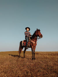 Full length of man riding horse on land against clear sky