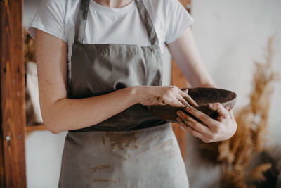 A girl in an apron sculpts from clay. hand work. creative profession. dirty hands. handmade 