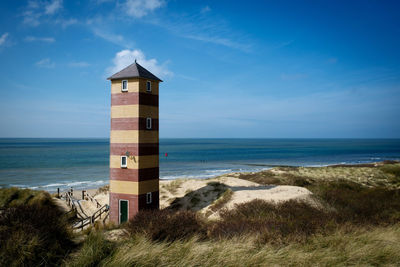 Lighthouse by sea against sky