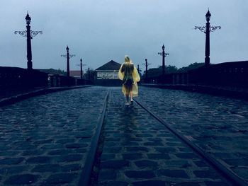 Rear view of woman walking on street during rainy season