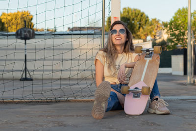Full length of young woman sitting on street