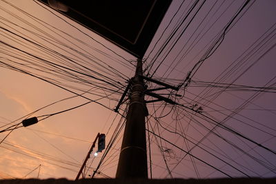 Low angle view of silhouette electricity pylon against sky at sunset