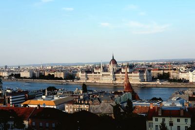 High angle view of buildings by river against sky in city