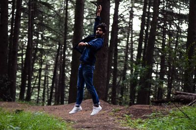 Man jumping against trees in forest