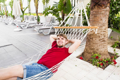 Portrait of young man lying down on hammock